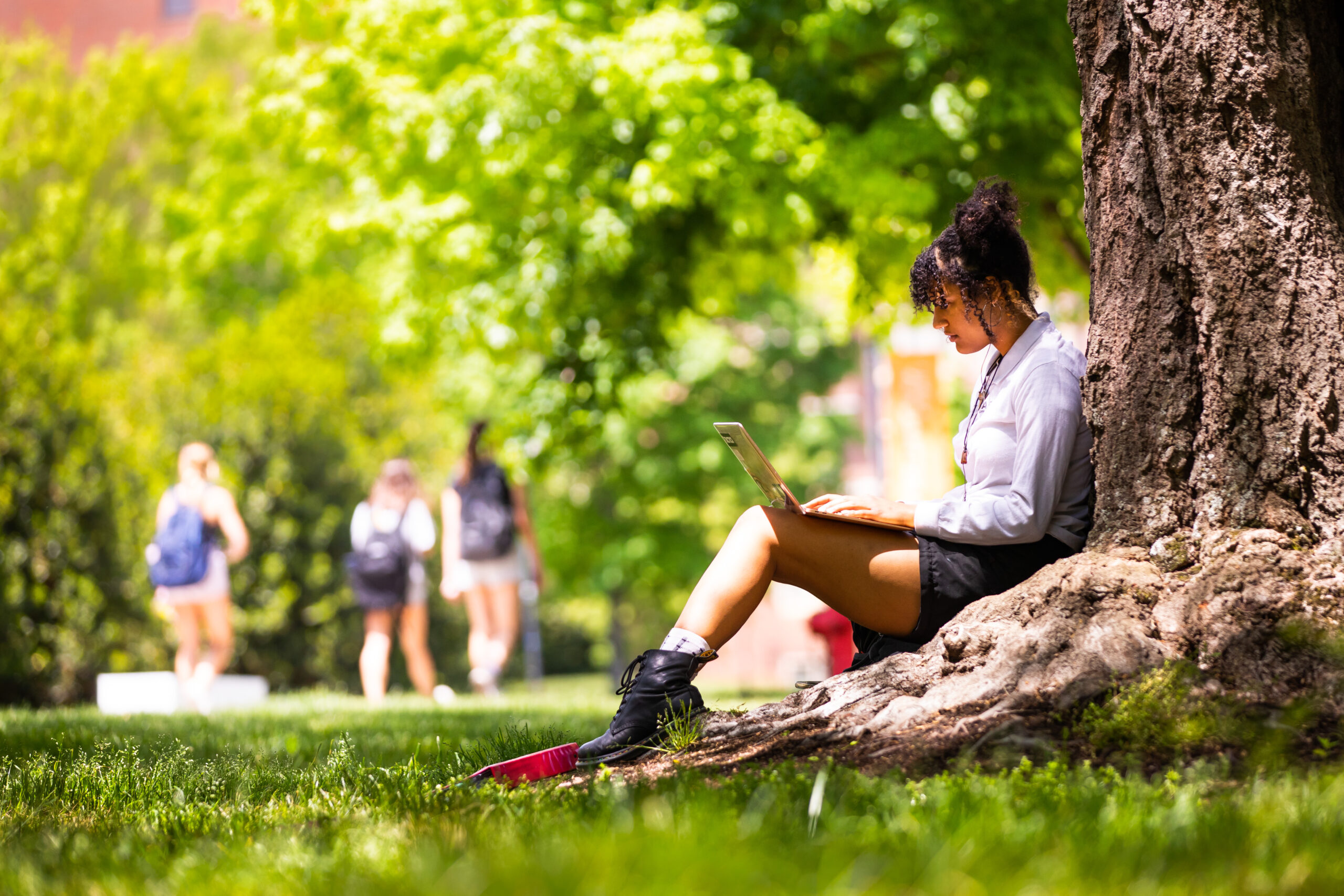 A student enjoys the outdoor weather while working on a laptop at the Humanities/Art & Architecture Quad